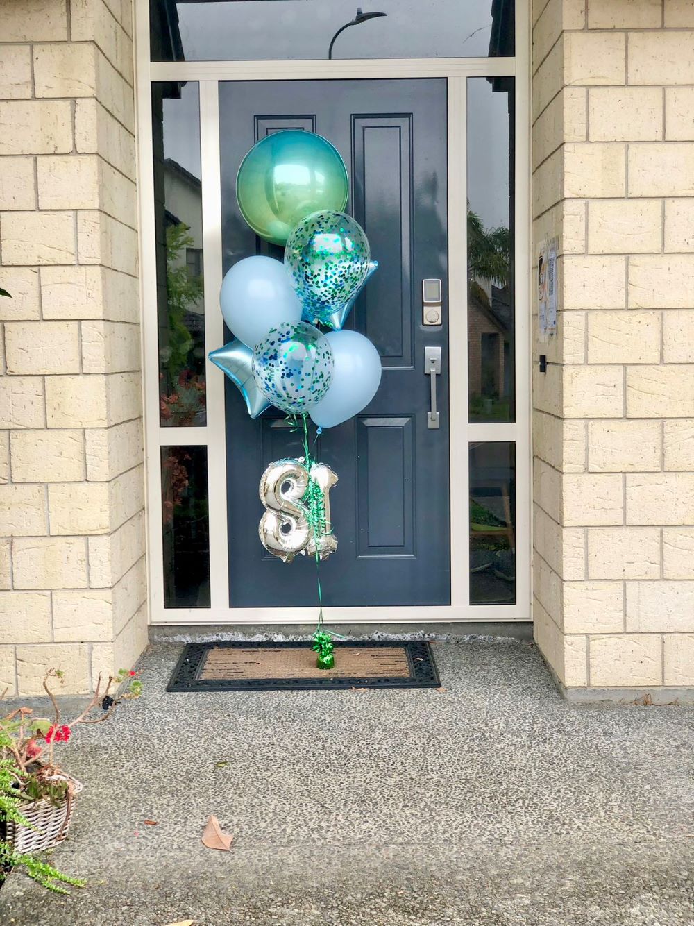 My Party Box Blue and Green Deluxe Balloon Bouquet with Orbz balloons, starts balloons, satin blue balloons and blue confetti balloons at front door
