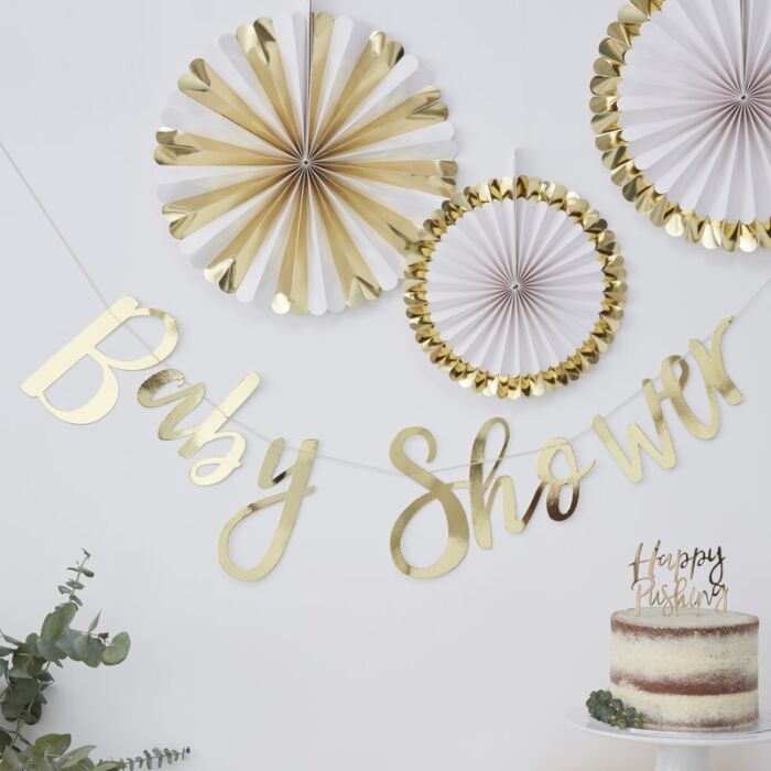 Ginger Ray Gold Baby Shower Garland hanging on white wall with Gold and White paper fan