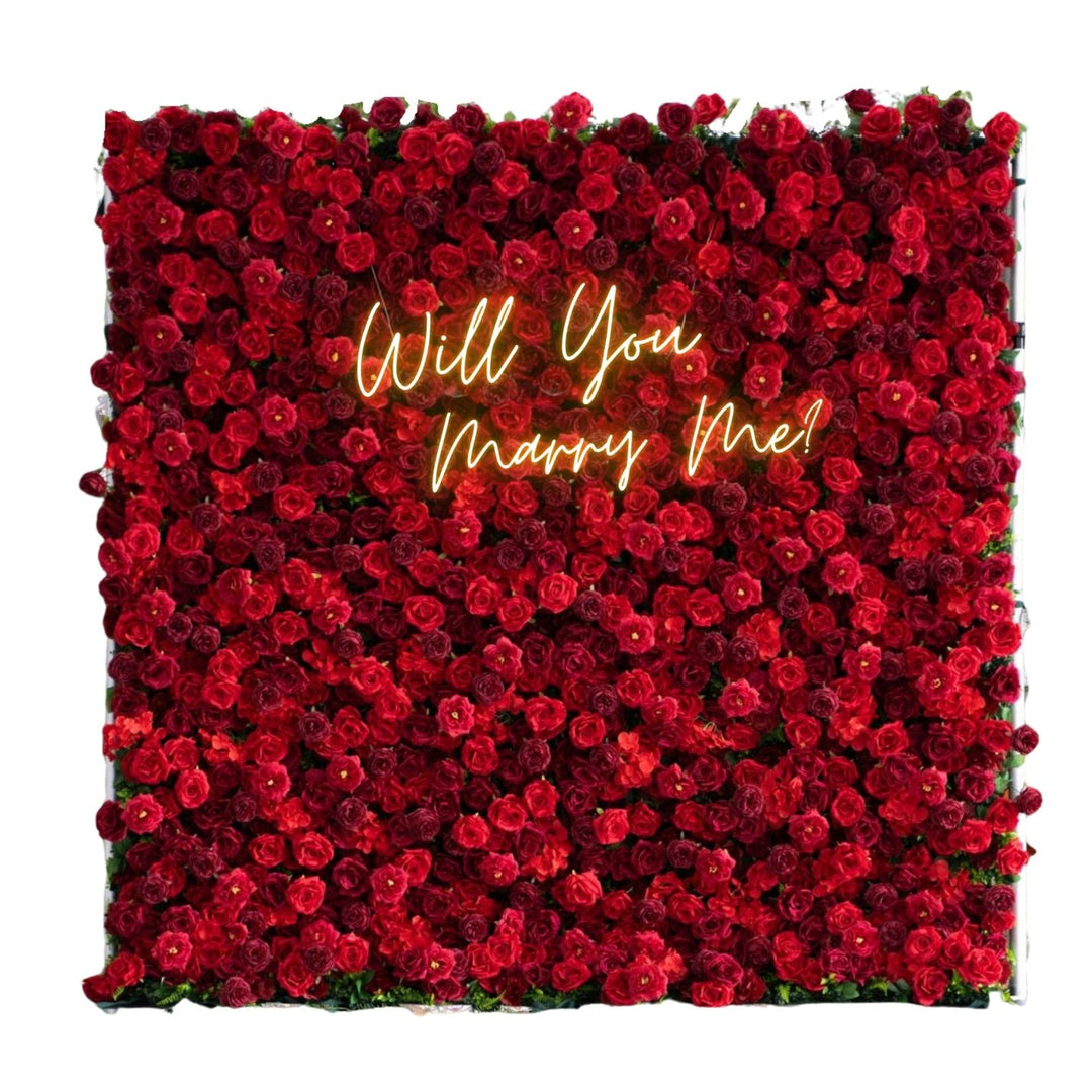 Wall of red roses with 'Will You Marry Me?' text in neon lights