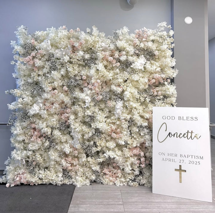 Floral wall with a sign for a baptism celebration