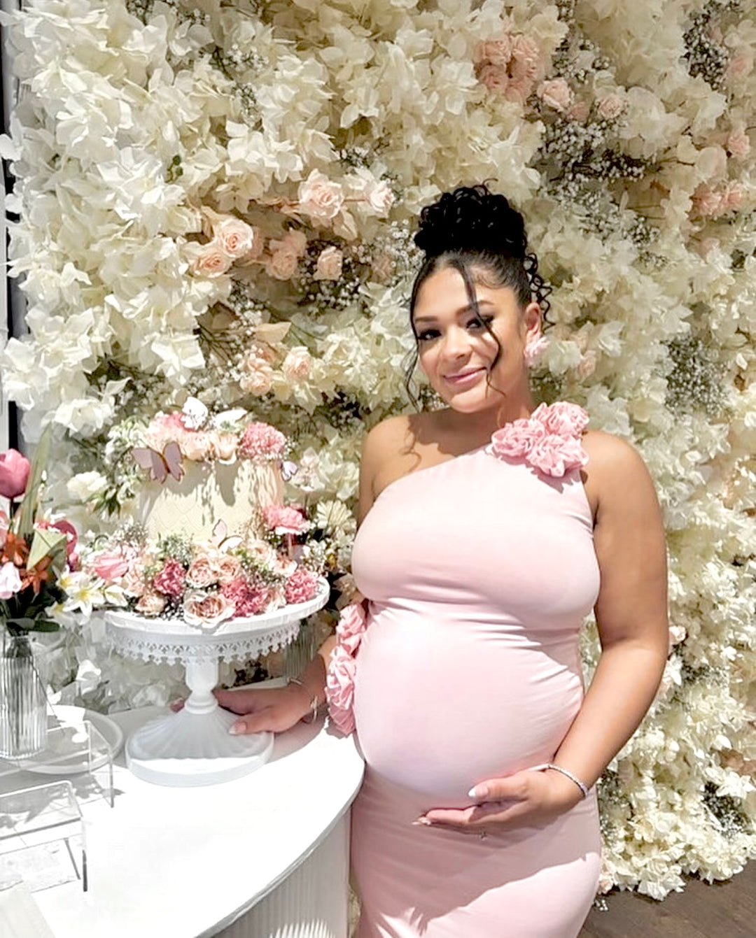 Woman in a pink dress standing in front of a floral backdrop