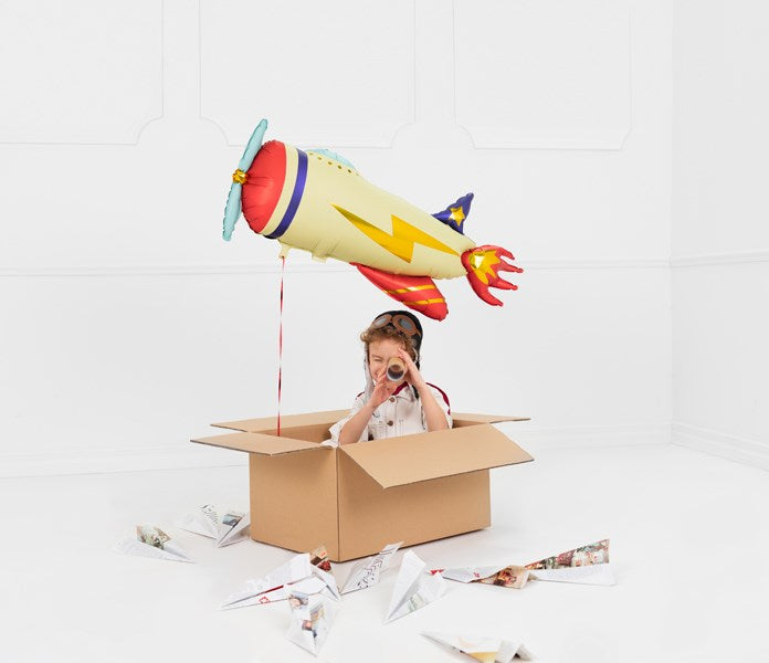 Child playing with a cardboard box and toy airplane against a white background