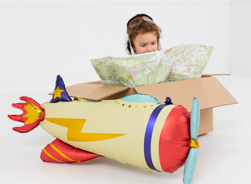 Child playing with a cardboard airplane costume on a white background