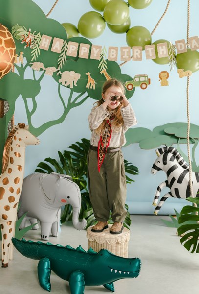 Child in safari outfit with birthday decorations and animal-themed props