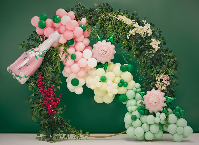 Decorative letter 'Q' made of balloons and flowers against a green background