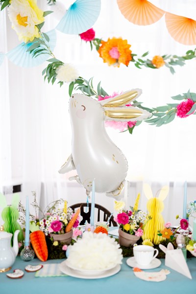 Decorative table setting with a rabbit-shaped balloon, flowers, and colorful decorations.