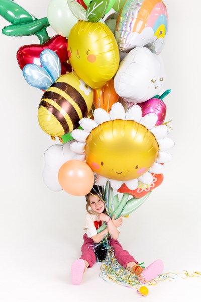 Child holding a bouquet of colorful balloons against a white background