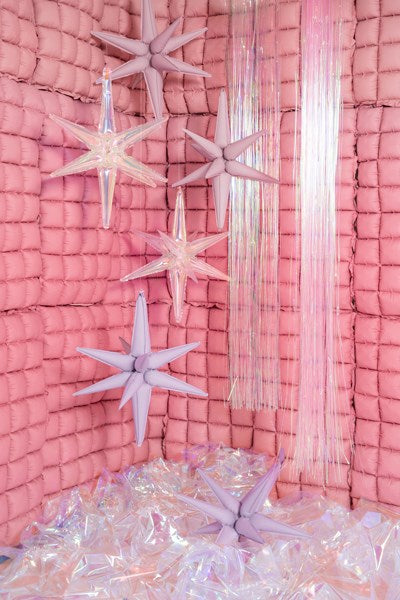 Decorative interior with pink textured walls, star-shaped ceiling lights, and a pink curtain.