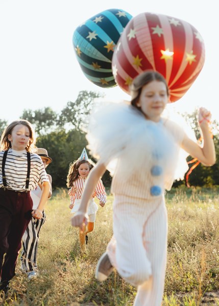 Children playing with colorful balloons in a field