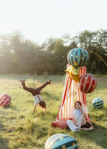 Two children playing with colorful balloons in a grassy field.