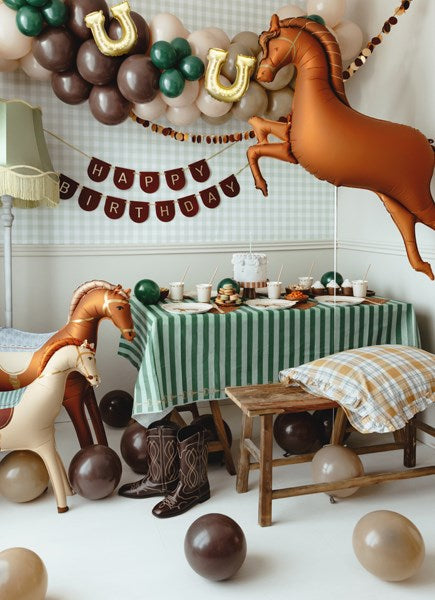 Birthday party setup with horse-themed decorations, balloons, and a tablecloth.