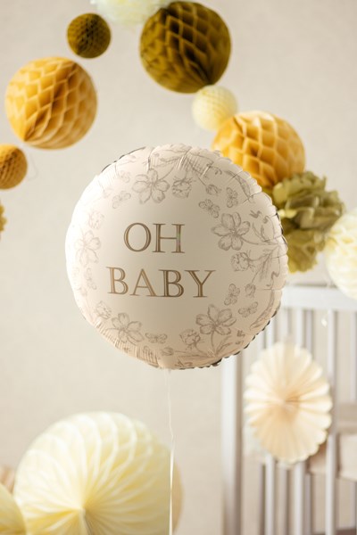 Decorative balloon with 'OH BABY' text among paper fans in a neutral setting