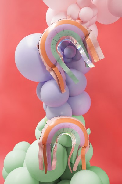 Colorful balloon arch with rainbow decorations on a pink background