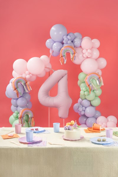 Decorative balloon arch with number '4' and rainbow elements on a table against a pink background