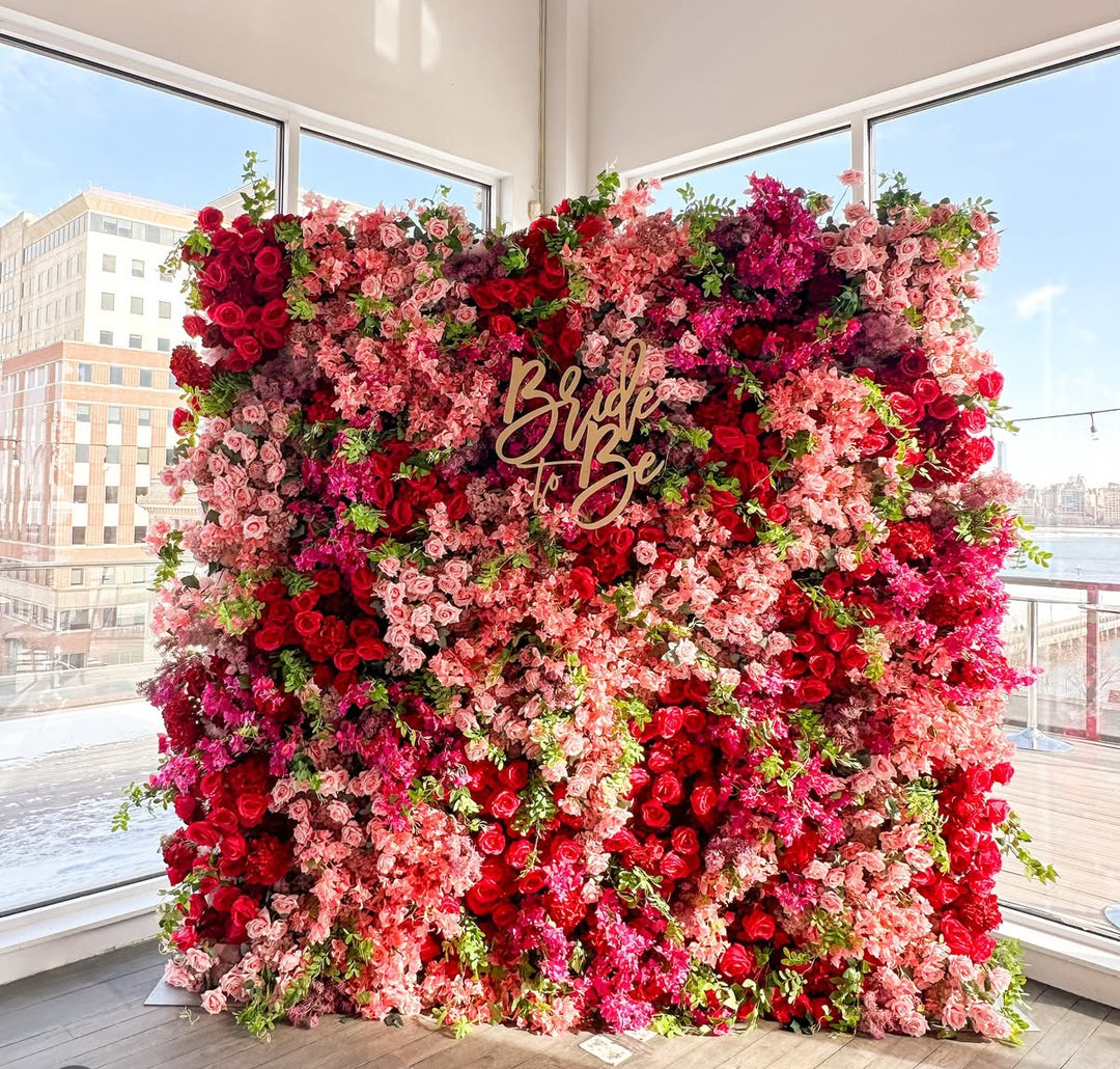Floral arrangement with 'Bride to Be' sign in a bright room with large windows.