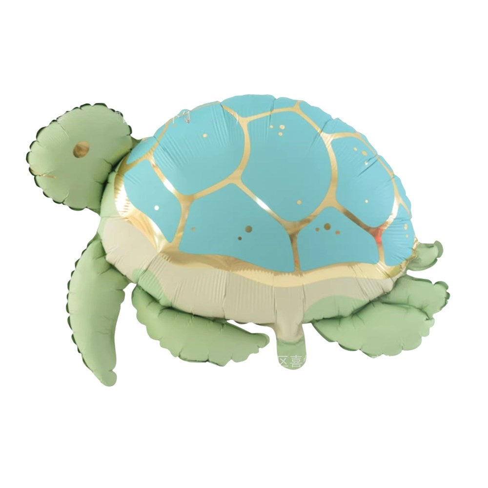 A foil balloon shaped like a sea turtle, featuring a light blue shell with gold lines, a cream-colored underside, and a light green head, flippers, and tail.