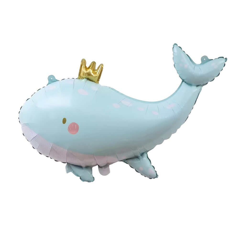 A light blue whale-shaped foil balloon with a small gold crown on its head, set against a plain white background.