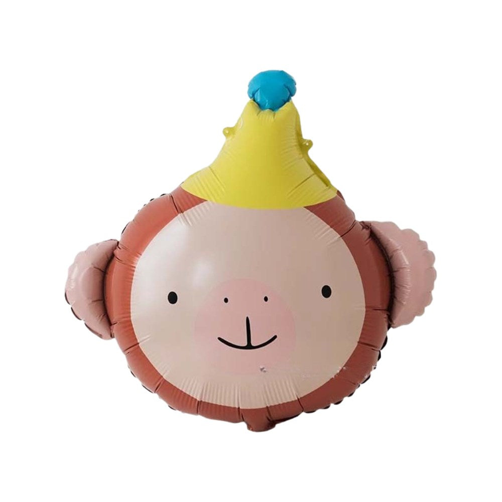 A novelty foil balloon shaped like a cartoon monkey face wearing a yellow party hat with a blue pom-pom, isolated on a white background.