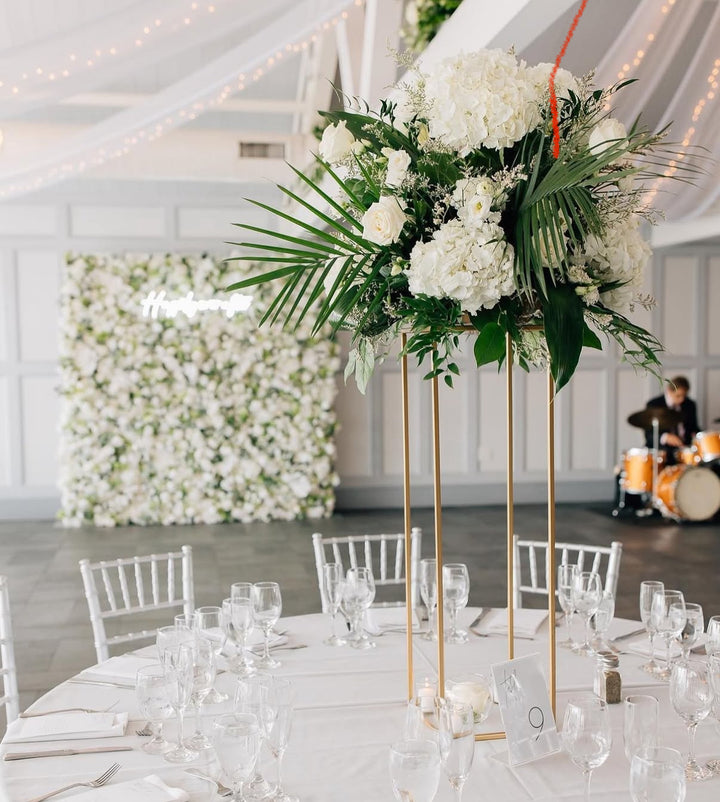 Decorative floral arrangement on a table with white chairs and a white wall in the background.