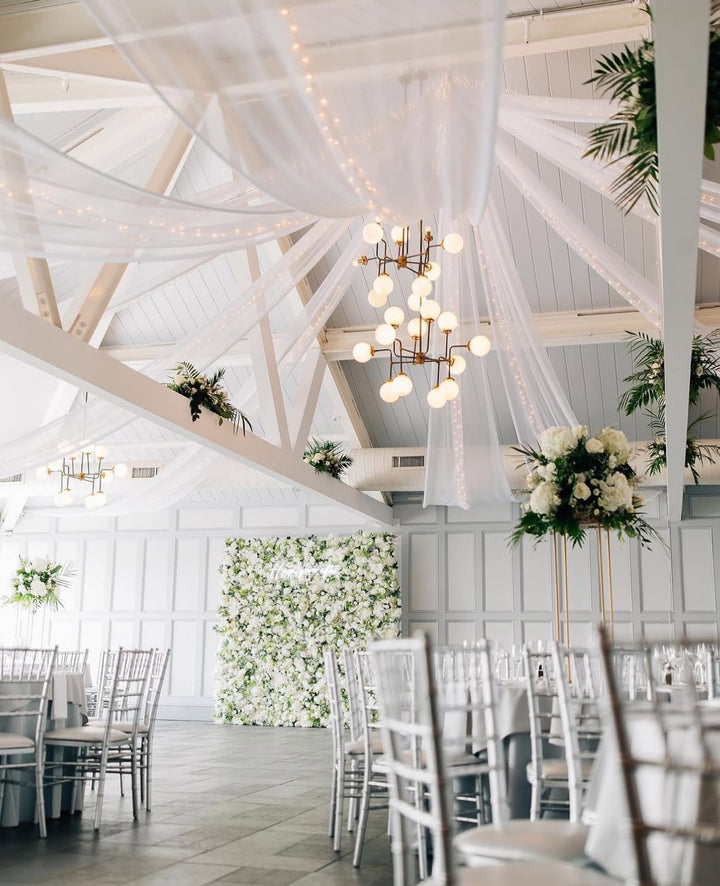 Decorated indoor setting with white walls, wooden beams, and floral arrangements.