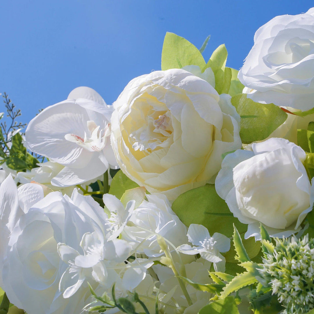 Bouquet of white flowers with green leaves against a clear blue sky