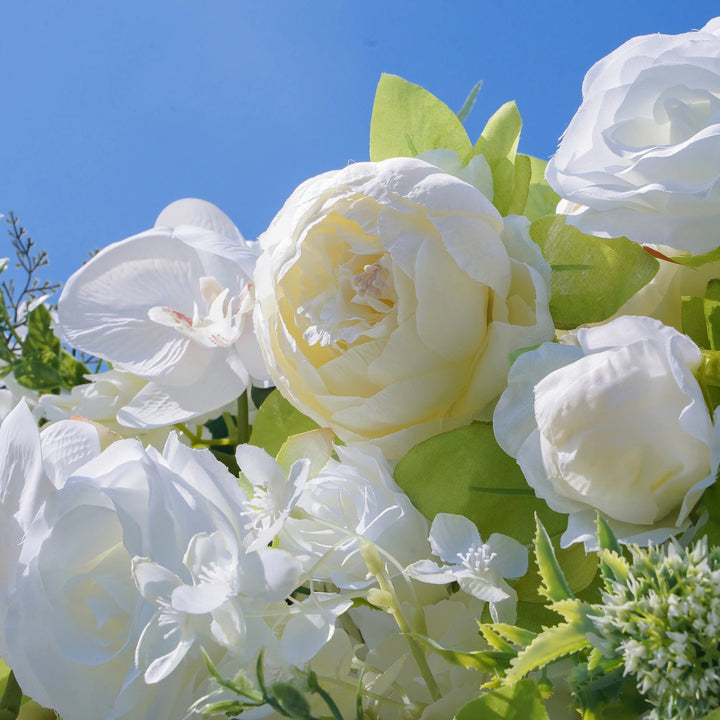 Bouquet of white flowers with green leaves against a clear blue sky