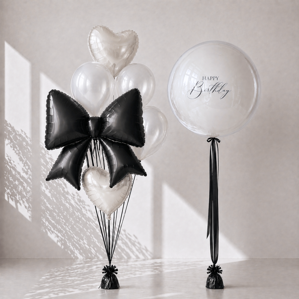 Decorative balloons with a large black bow and heart shapes on a light background
