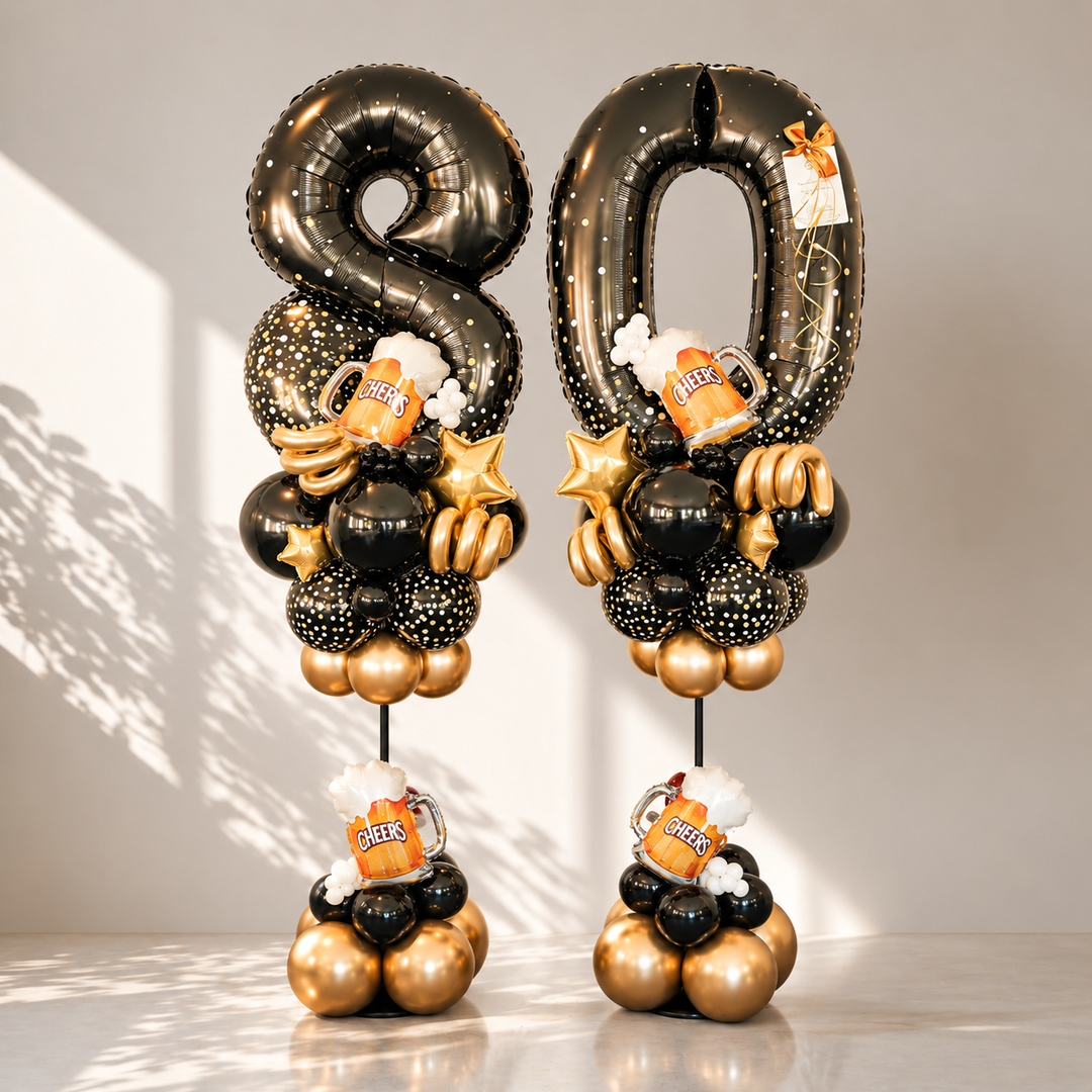 Two black and gold 80th birthday balloon towers decorated with foil balloons, gold stars, and beer mug toppers, set against a neutral studio background with soft shadows.