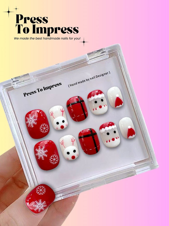 A hand holds a clear plastic case displaying 10 Christmas-themed press-on nails. The nails feature red and white holiday designs including snowflakes, Santa faces, plaid patterns, and reindeer.