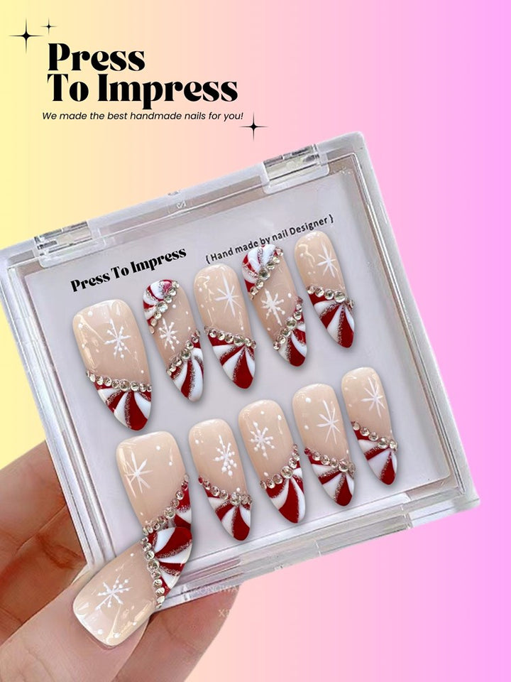 A hand holds a clear plastic case displaying press-on nails with a beige base, white snowflakes, and red-and-white candy cane patterns. The background is a pink-to-yellow gradient with the text 'Press To Impress' in the upper left.