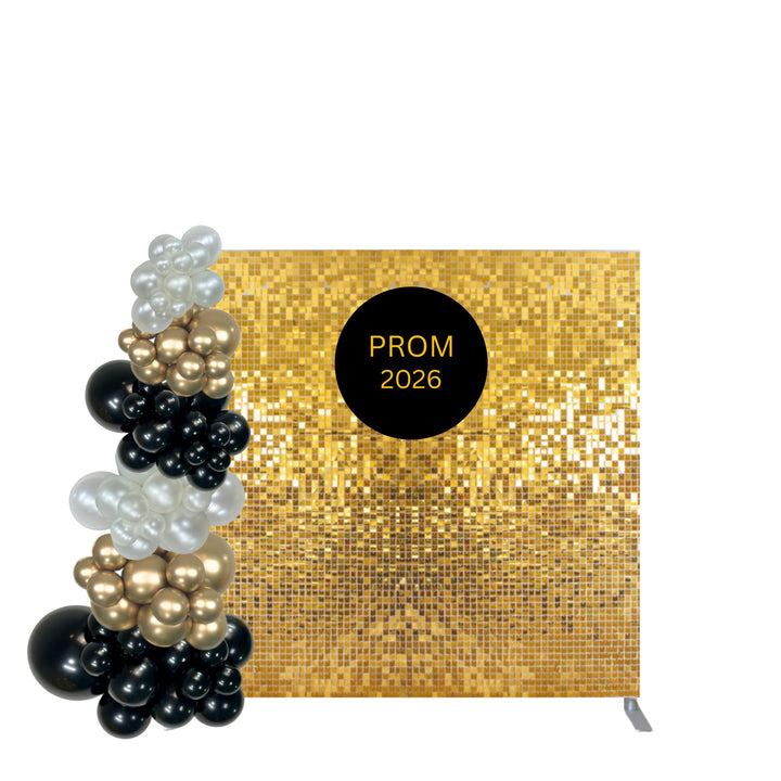 A gold sequin backdrop banner with a black circular sticker reading 'PROM 2026' in gold lettering, shown alongside a balloon garland of black, gold, and white balloons on a white background.