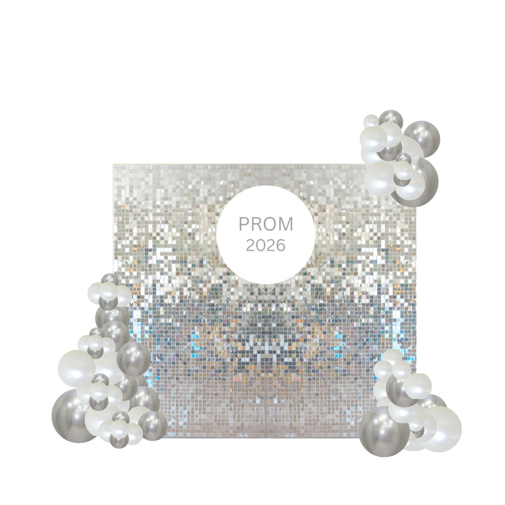 A square silver glitter backdrop with a central white circle reading 'PROM 2026', decorated with clusters of silver and white balloons in the corners on a plain white background.