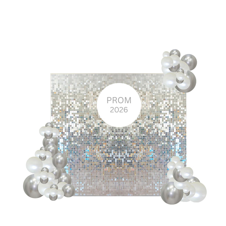 A square silver glitter backdrop with a central white circle reading 'PROM 2026', decorated with clusters of silver and white balloons in the corners on a plain white background.