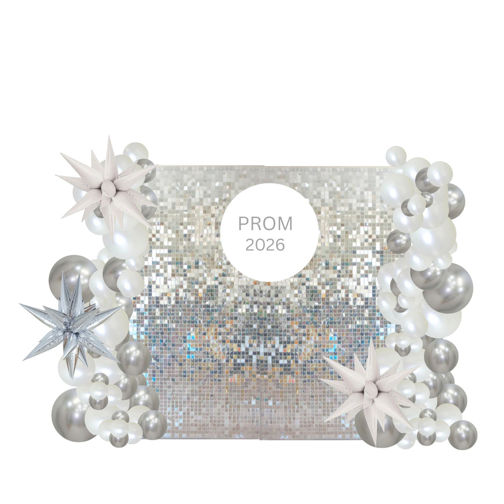 A square silver sequin backdrop decorated with white and silver balloon garlands, star-shaped balloons, and a central white circle reading 'PROM 2026'.