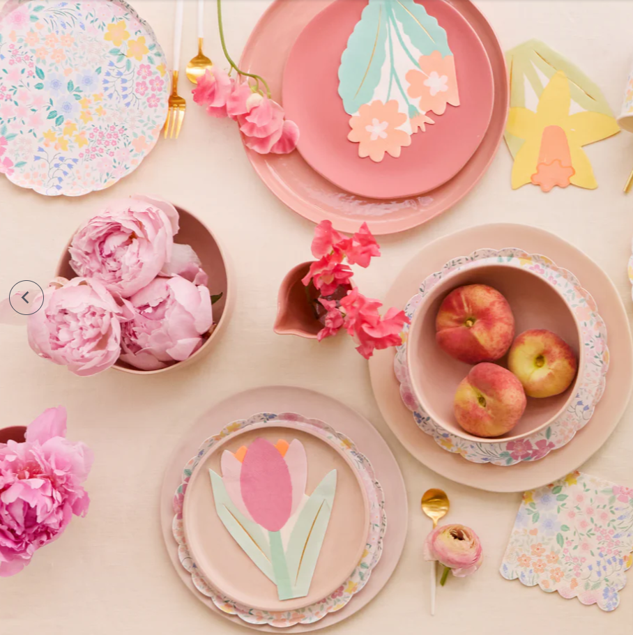Pastel-colored tableware with floral designs and pink flowers on a light background