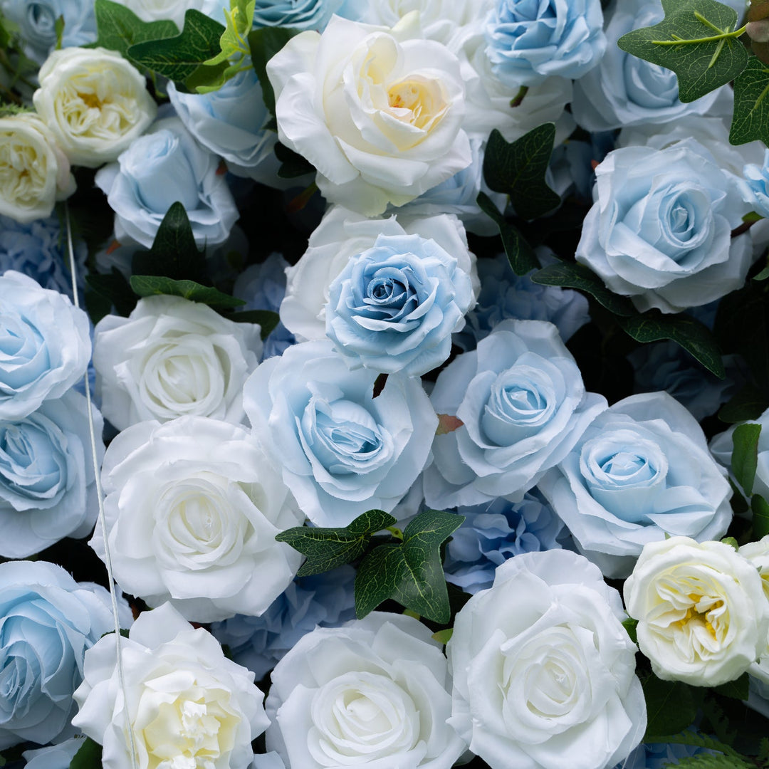 Close-up of blue and white artificial roses with green leaves.