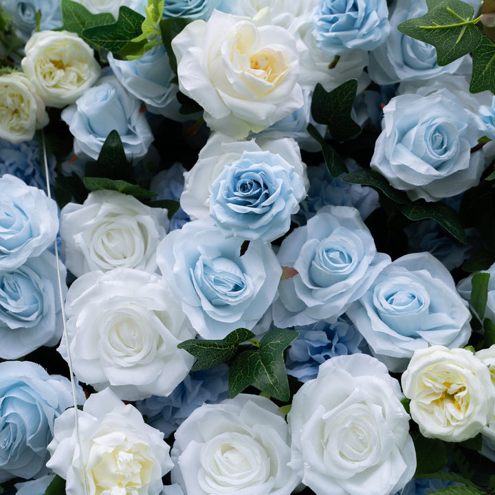 Close-up of blue and white artificial roses with green leaves.