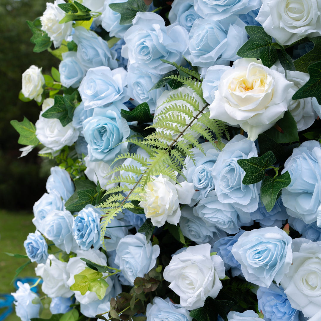 Decorative arch made of blue and white artificial roses with green leaves.