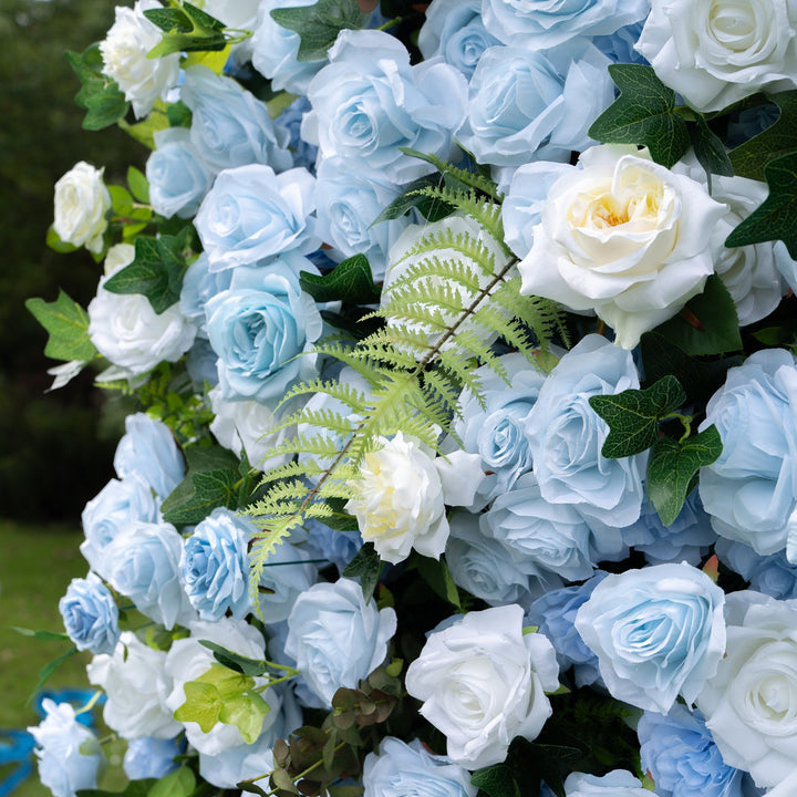 Decorative arch made of blue and white artificial roses with green leaves.
