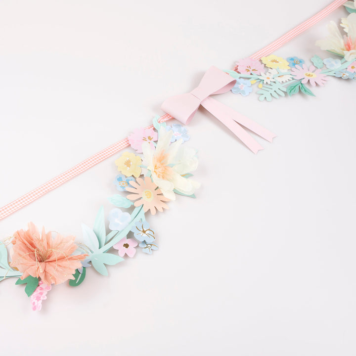 Floral headband with pastel flowers and a pink bow on a white background