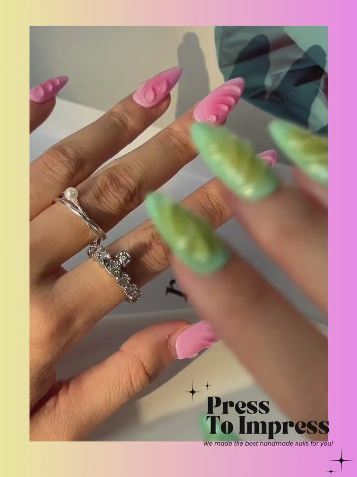 A Video shows A hand holds a clear plastic case displaying 10 press-on nails with pink and green leaf-like patterns, set against a pink and yellow gradient background with 'Press To Impress' branding.