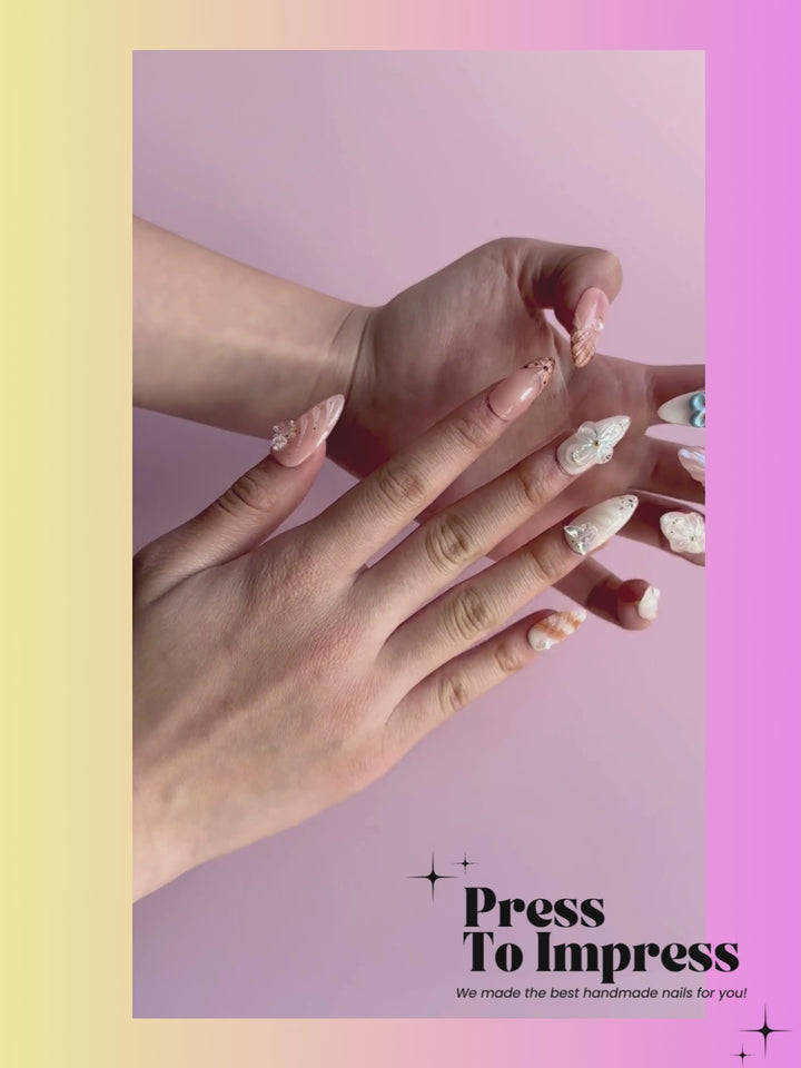 Video shows A hand holds a clear plastic case displaying ten decorative press-on nails. The nails feature pastel peach, mint green, cream, and orange designs with floral, shell, and glitter details.