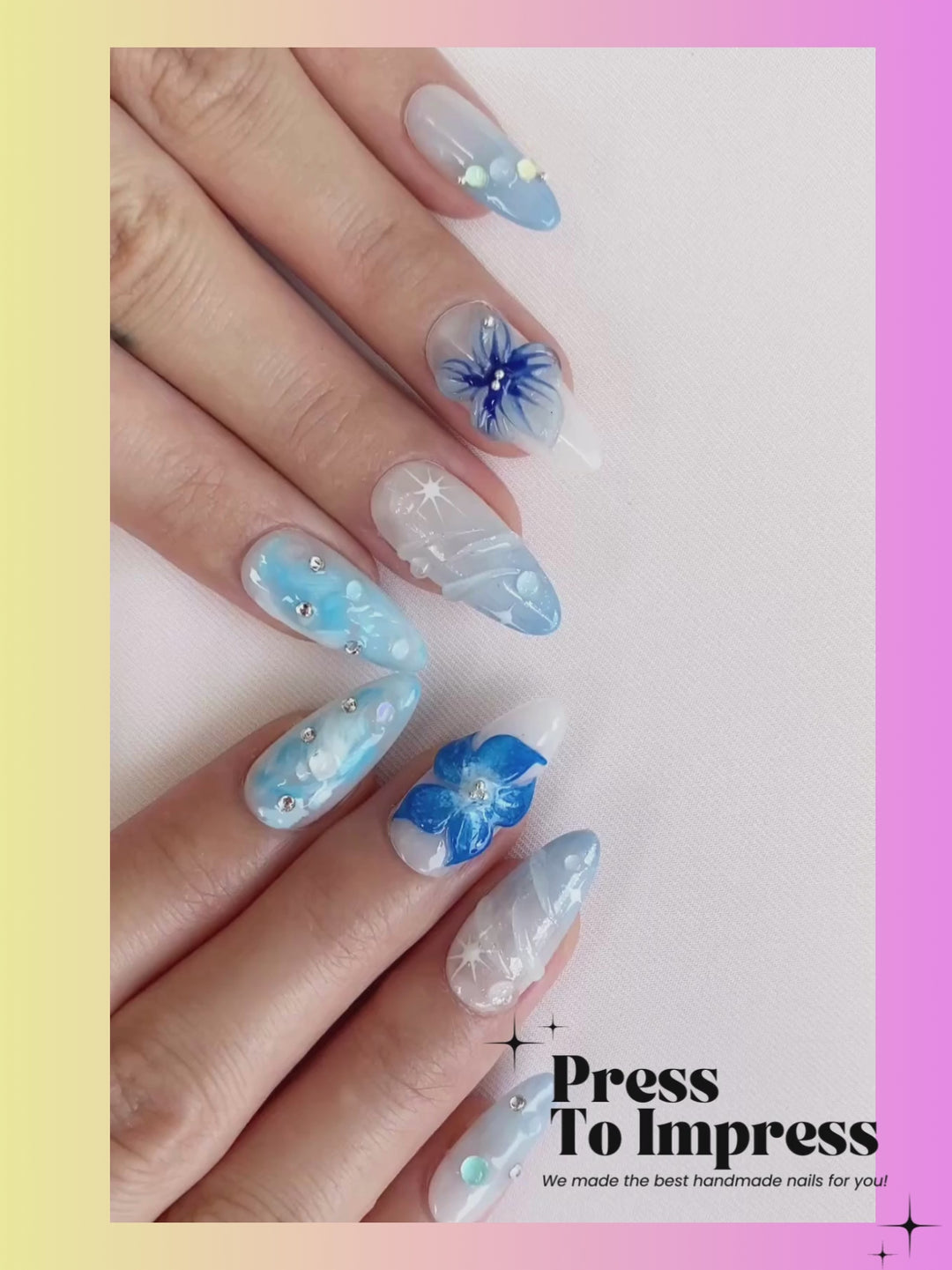 A Video shows A hand holds a clear plastic case displaying 10 press-on nails with blue and white floral, swirled, and glitter designs against a pink and yellow gradient background with 'Press To Impress' branding.