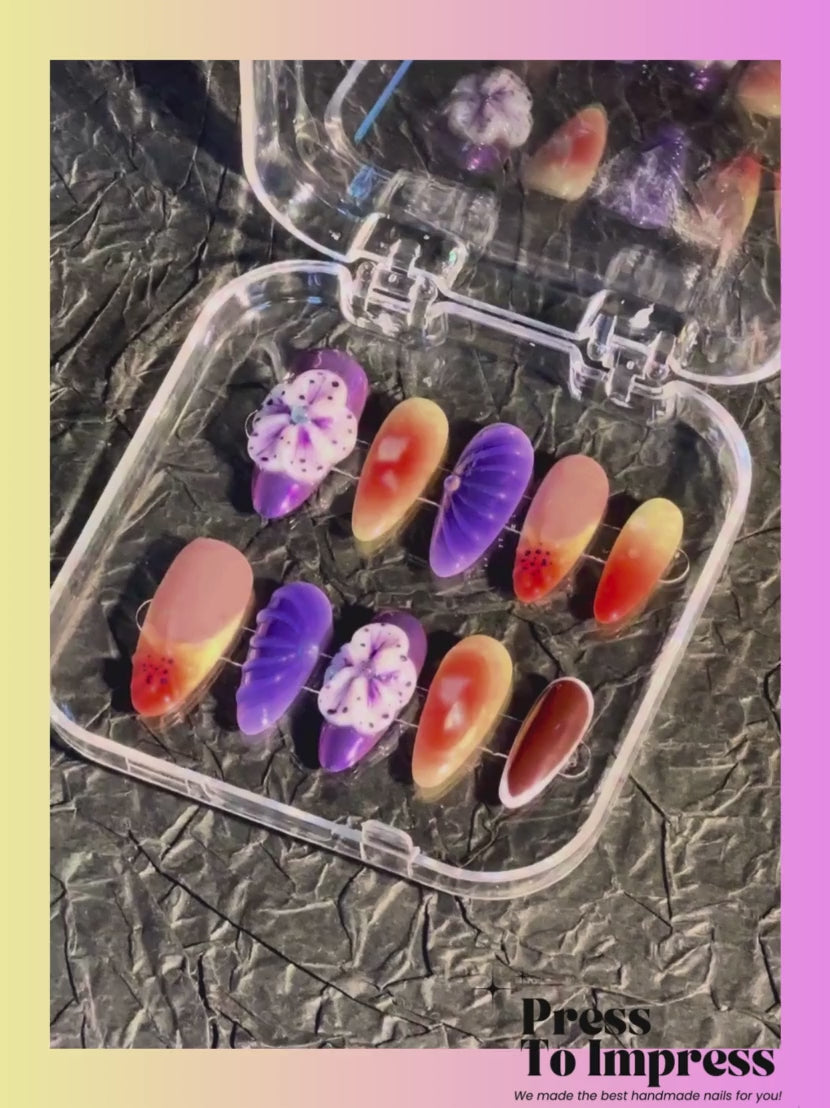 A Video shows A hand holds a clear plastic case displaying ten press-on nails with various designs including purple flowers, orange-to-yellow gradients, and solid black, against a pink and yellow gradient background with 'Press To Impress' branding.