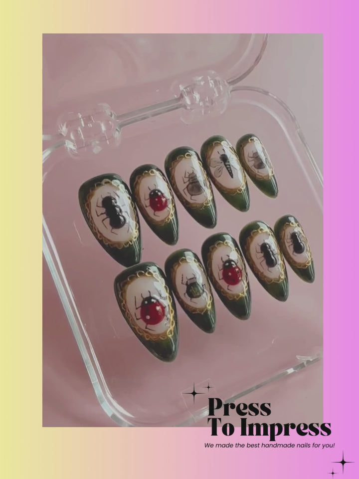 A video shows A hand holds a clear plastic case containing ten decorative press-on nails with a dark green base, gold glitter borders, and various insect and ladybug illustrations. The background is a soft pink-to-yellow gradient with the text 'Press To Impress' in the upper left.