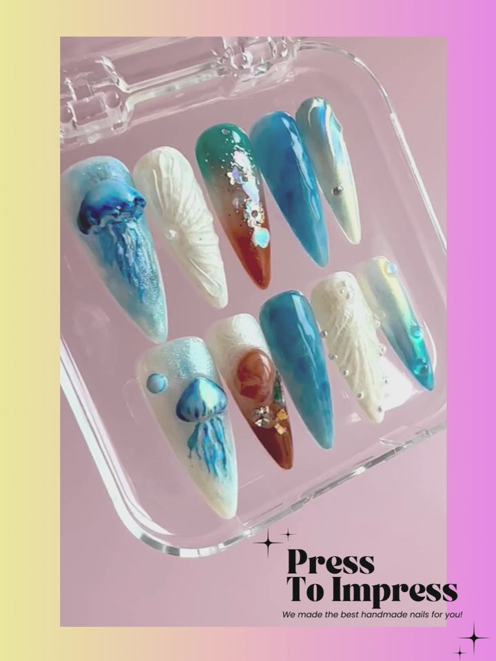 A Video shows A hand holds a clear plastic case displaying ten press-on nails with ocean-inspired designs, including blue jellyfish, white seashells, and blue-and-white gradient nails, against a pink-to-yellow gradient background with 'Press To Impress' text.