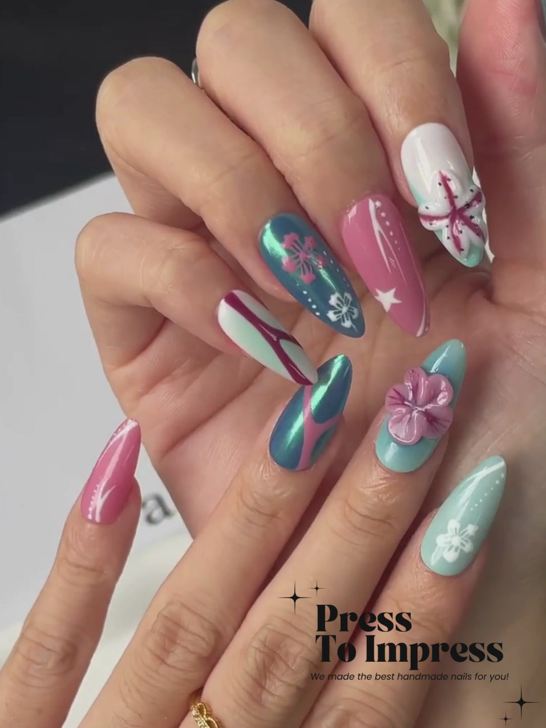 A Video shows A hand holds a clear plastic case displaying 10 press-on nails with a tropical beach theme, including turquoise, pink, white, and blue designs with starfish and floral details. The background is a soft pink-to-yellow gradient with the text 'Press To Impress' in the top left.