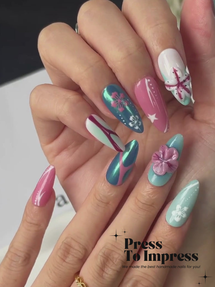 A Video shows A hand holds a clear plastic case displaying 10 press-on nails with a tropical beach theme, including turquoise, pink, white, and blue designs with starfish and floral details. The background is a soft pink-to-yellow gradient with the text 'Press To Impress' in the top left.