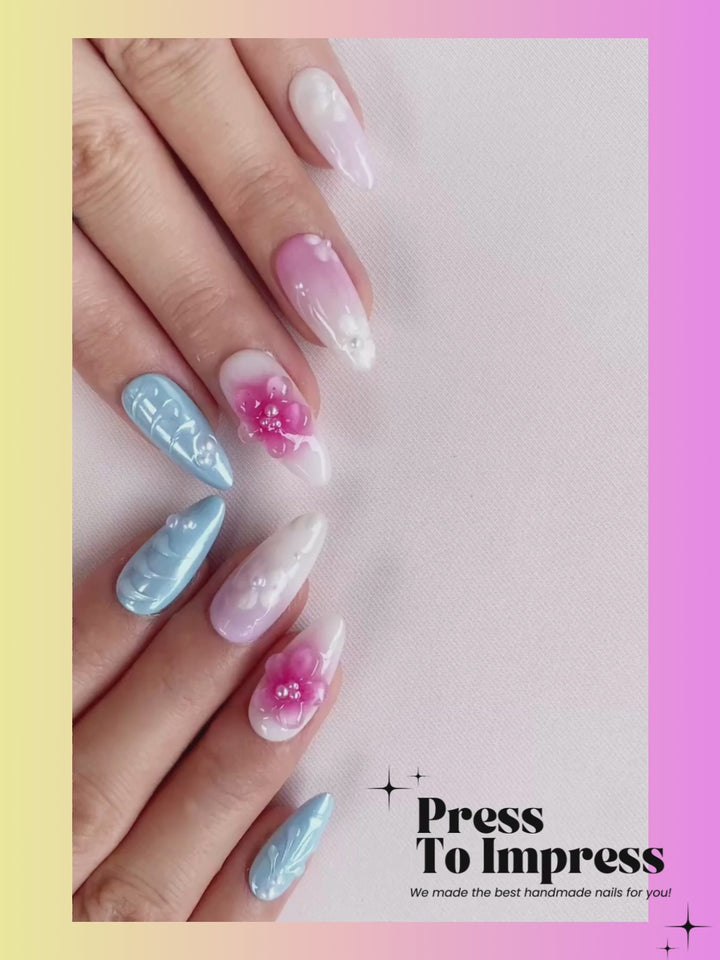 Video shows A hand holds a clear plastic case displaying 10 press-on nails with pastel gradients, floral designs, and glitter details against a pink and yellow gradient background with 'Press To Impress' branding.