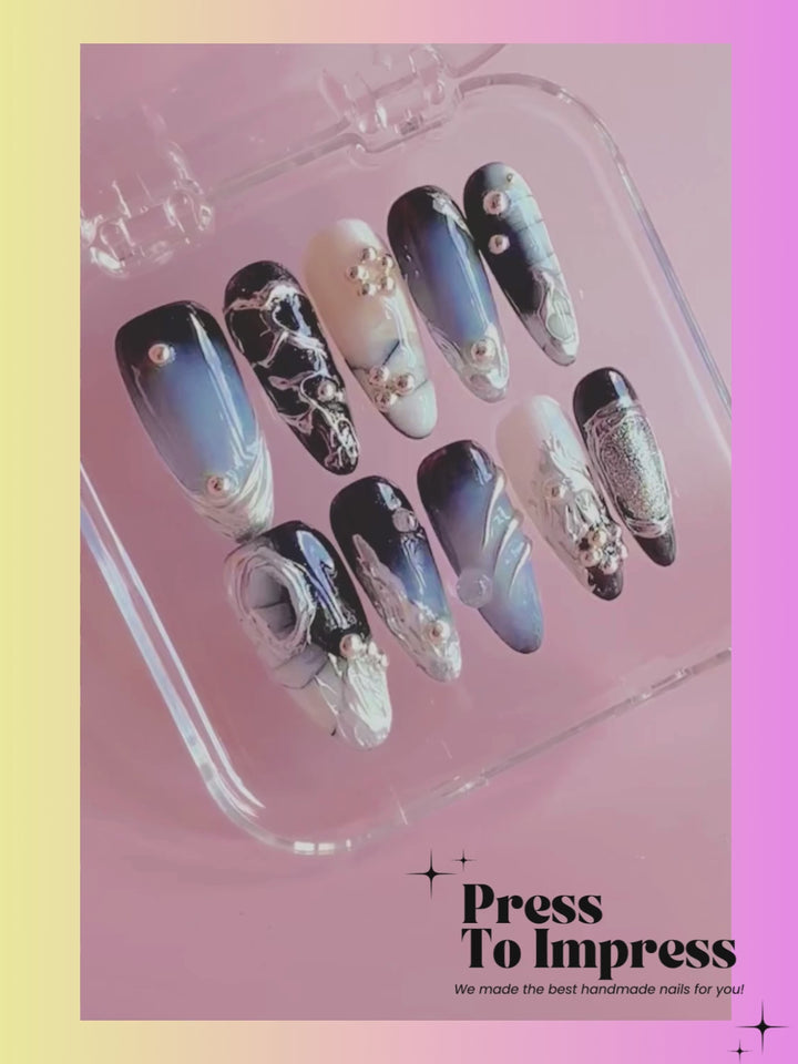 Video shows A hand holds a clear plastic case displaying 10 press-on nails with blue, black, white, and silver gradient designs and rhinestone accents. The background is a pink-to-yellow gradient with the text 'Press To Impress' in the top left.